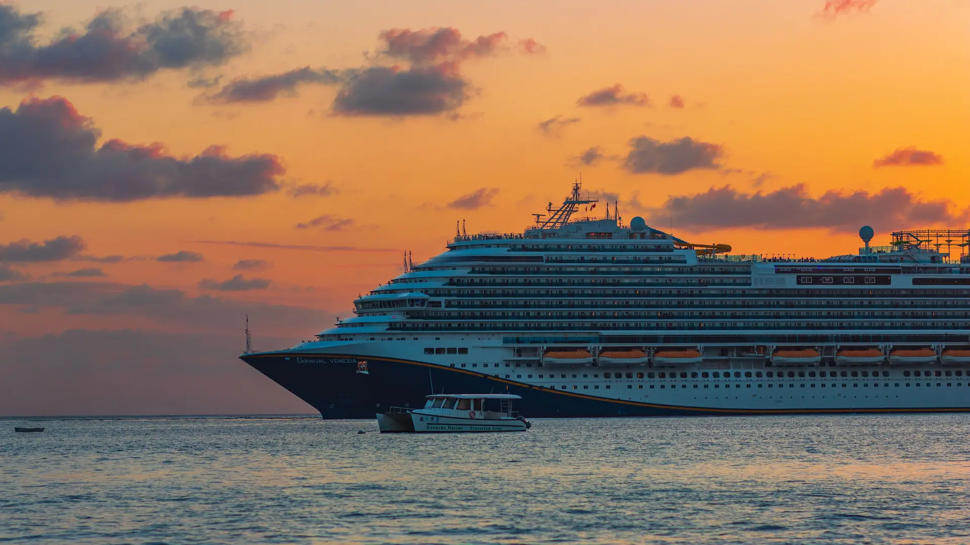 A cruise ship at anchor against a sunset sky