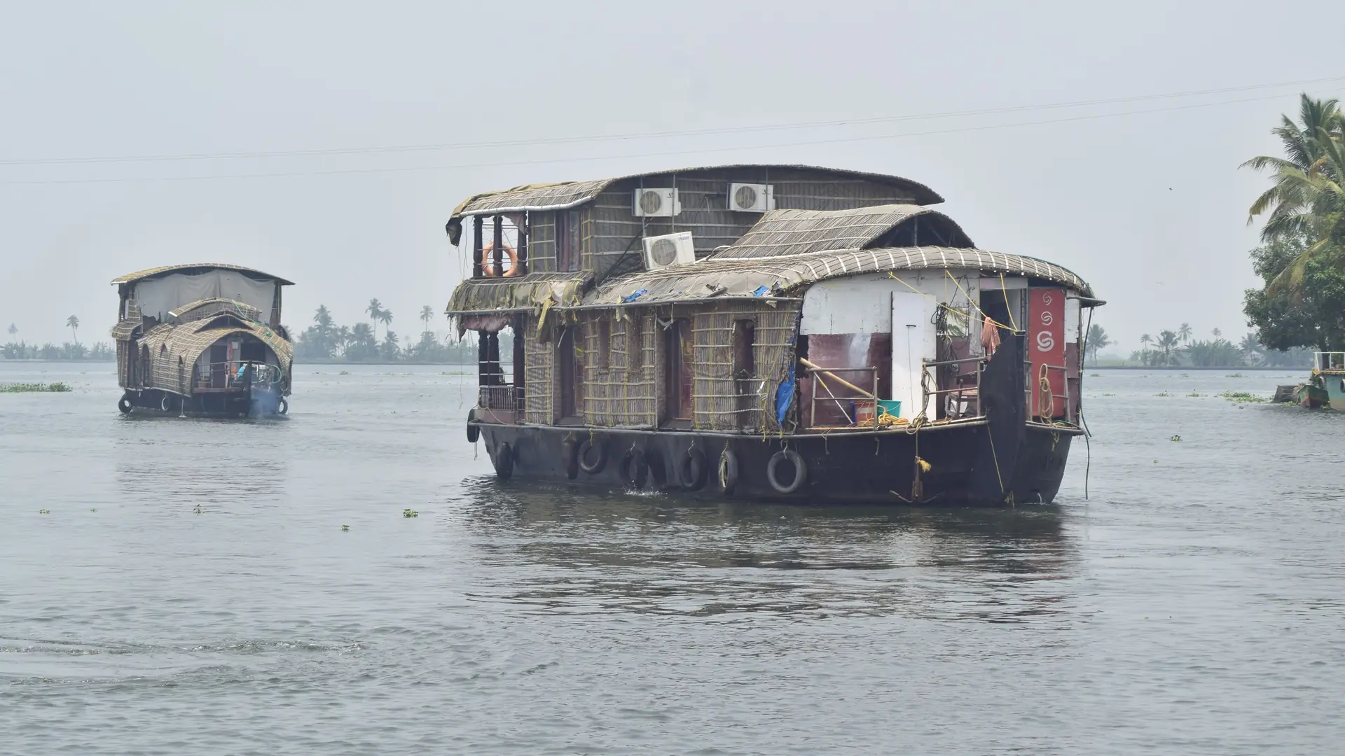 A houseboat on the wide grey water of the backwaters of Kerala
