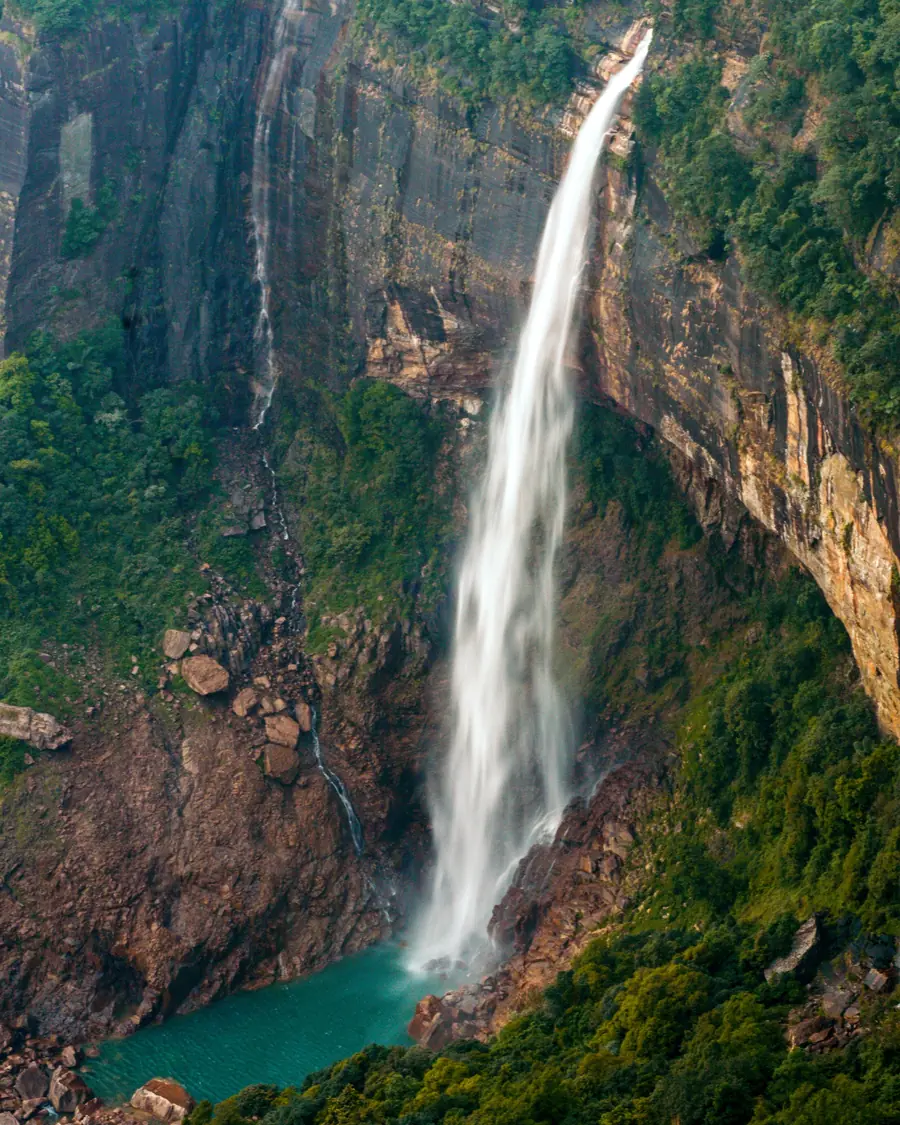 Nohkalikai falls dropping into a green pool in Meghalaya