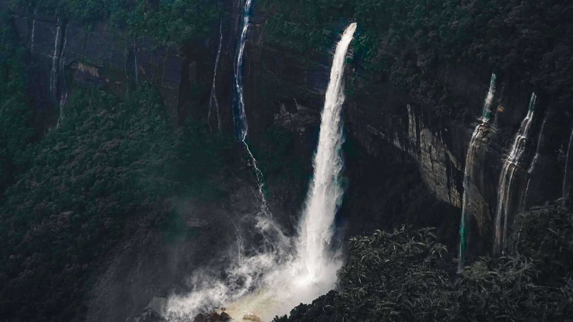 A waterfall dropping off a forested cliff near Shillong, Meghalaya